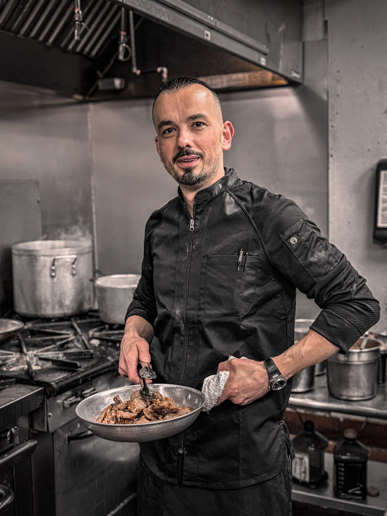 Tony Avanzare at the stove in the La Bocca kitchen, holding a pan